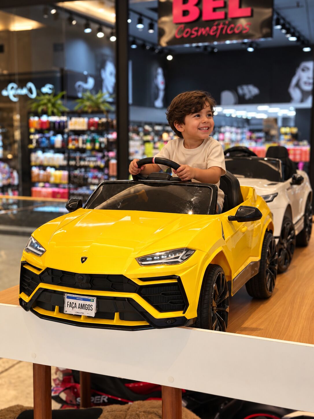 Menino sorrindo ao volante da Lamborghini Urus amarela do FaçaAmigos Circuito
